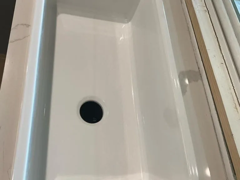 A new white undermount sink set in a white quartz counter, with its drain opening still empty